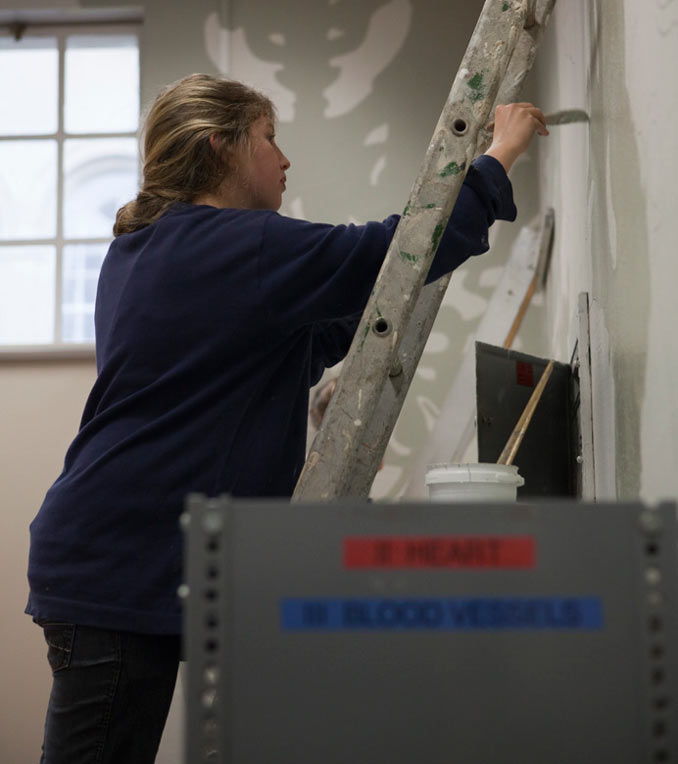 Photo of Sarah Biggs painting mural in PLC