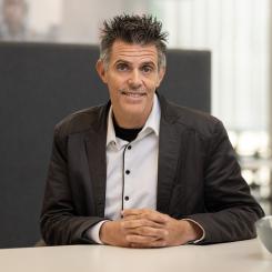 A photograph of Reto Guler sitting at a desk