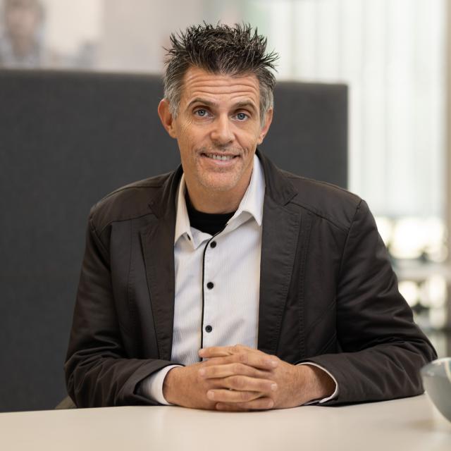 A photograph of Reto Guler sitting at a desk