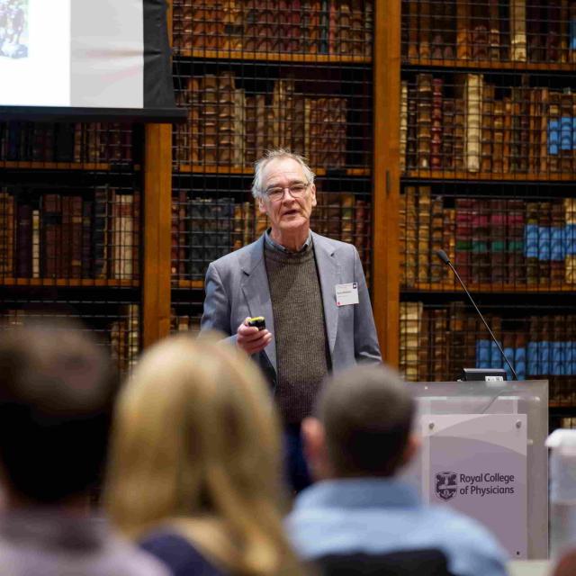 Prof. Robert J Wilkinson presenting to an audience in a library