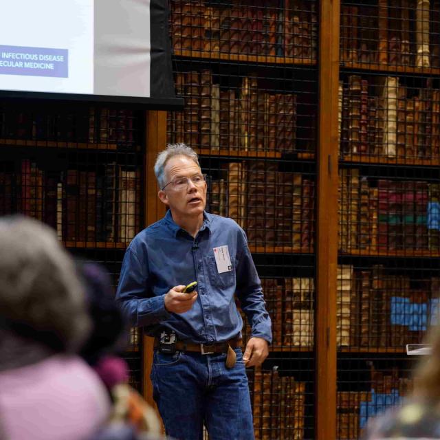 Prof. Digby Warner presents to an audience in a library