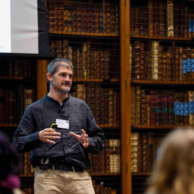 Prof. Andrew Boulle stands in front of a shelf of books in a library